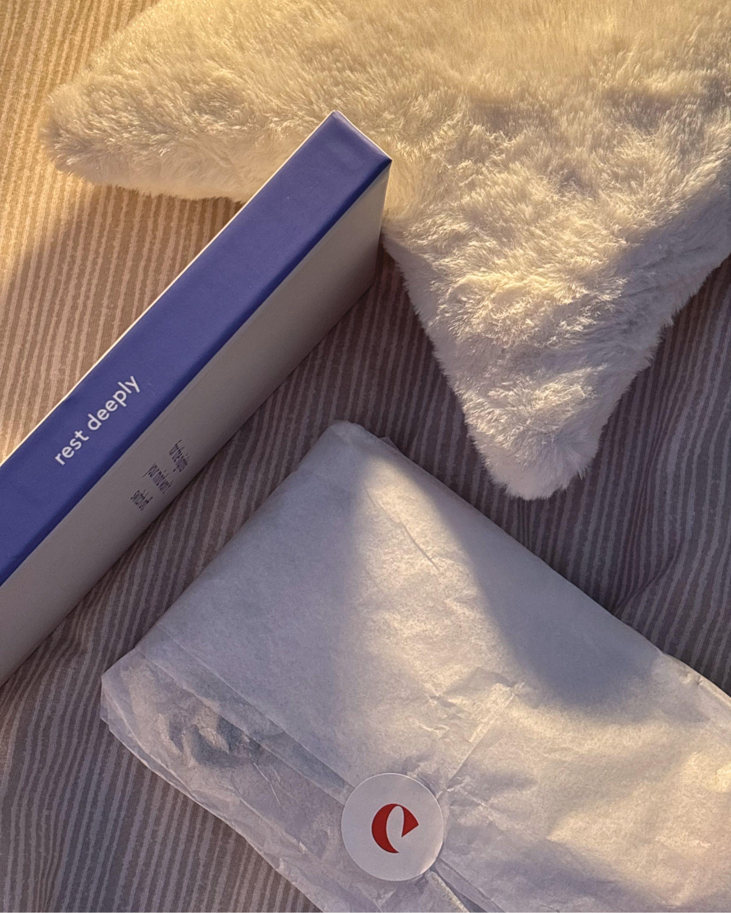 The Clementine box and a tissue-wrapped parcel on a striped bed in evening light