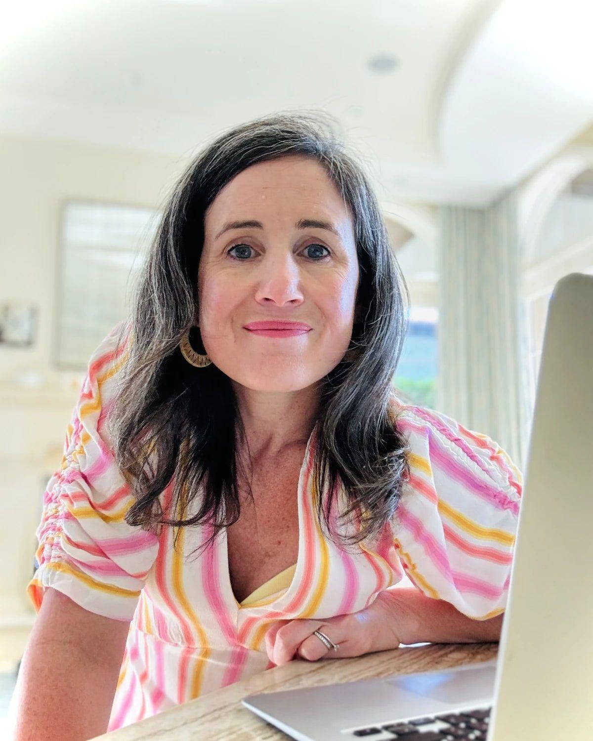 Kim Palmer, founder of Clementine, smiling at her kitchen table beside her laptop