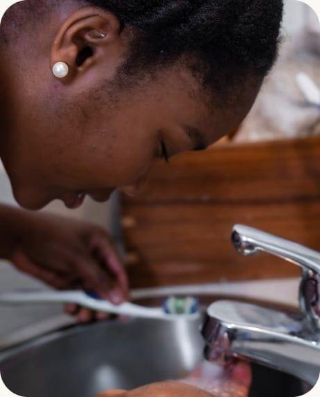 A woman splashing water on her face at a sink