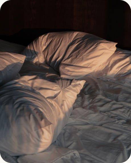 Crumpled bedsheets in a dark bedroom