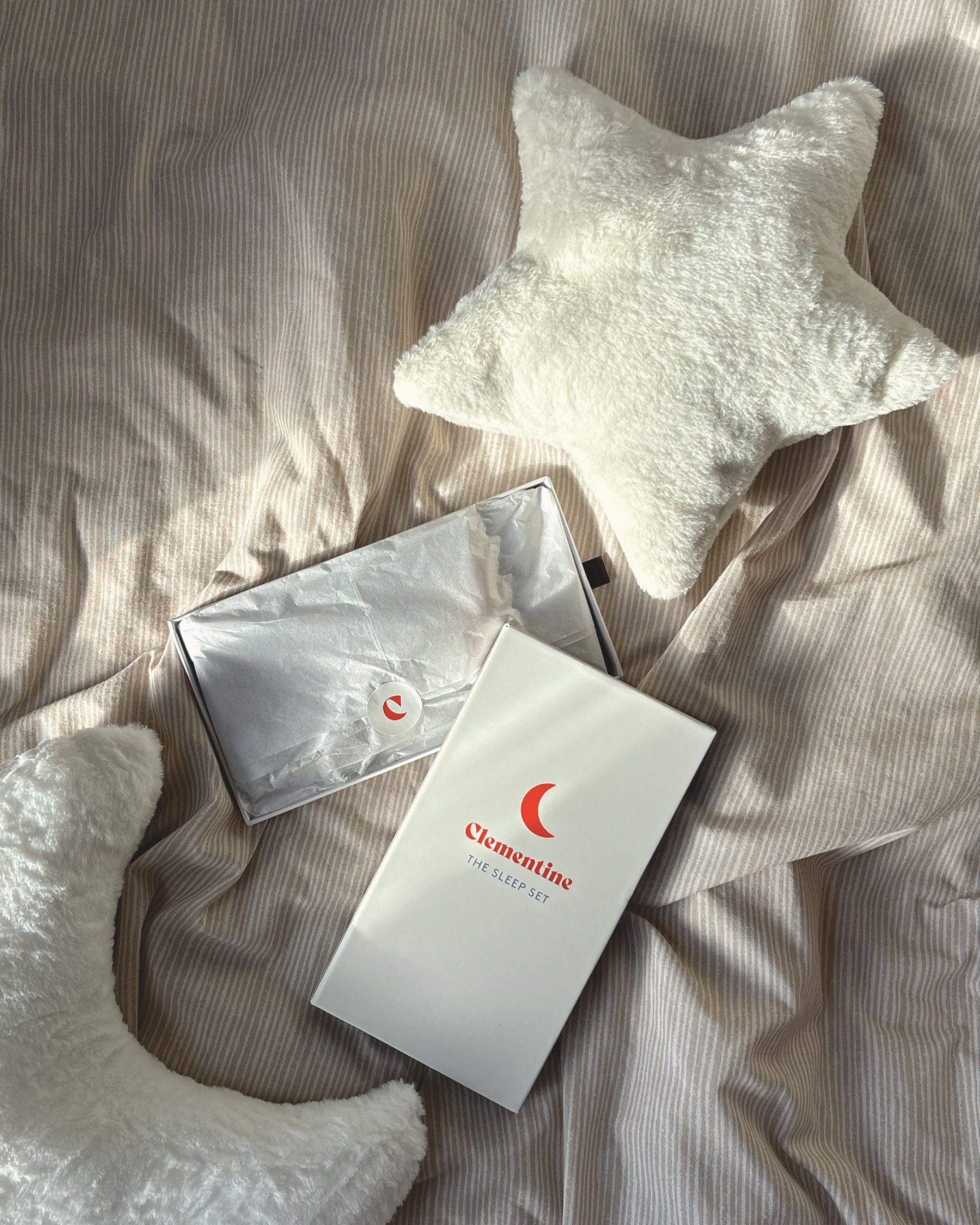 The Clementine box opened on a bed, with tissue paper and a star cushion